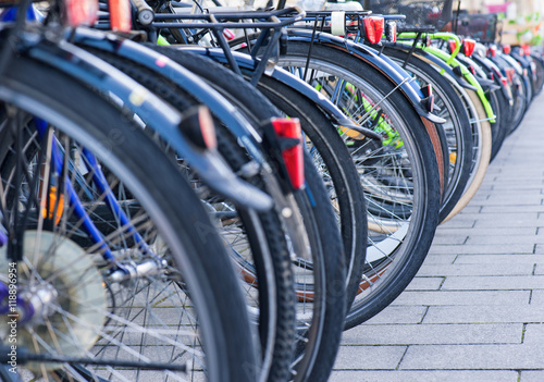 Group of bicycles in the row on sidewalk. Selective focus. Parking for bikes in big European city. Close up of wheel.