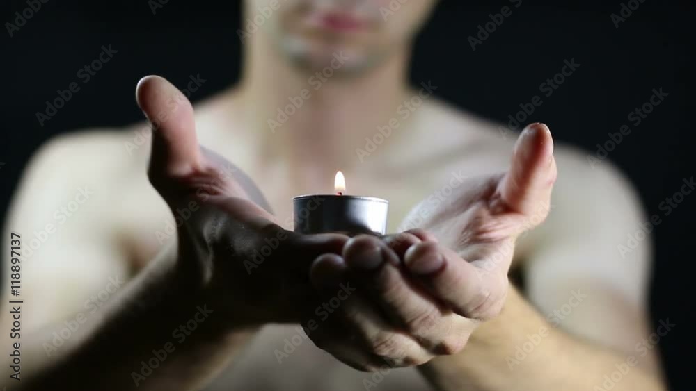 hands holding a burning candle in dark hands holding a burning candle in dark