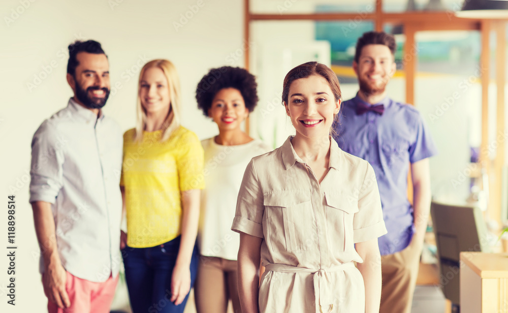 Fototapeta premium happy young woman over creative team in office