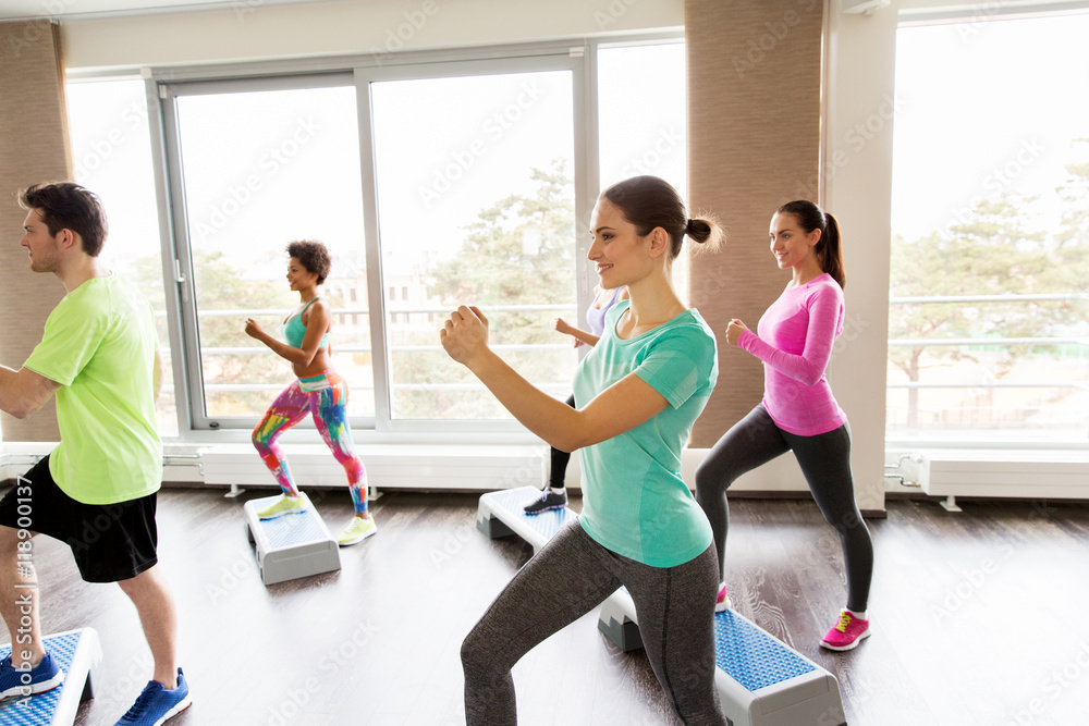 group of people exercising on steppers in gym group of people exercising on steppers in gym