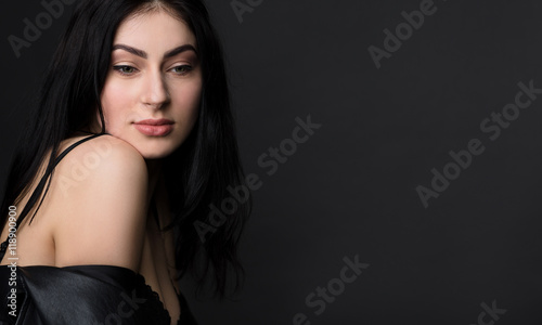 Portrait of happy smiling beautiful brunnette model woman posing in black lingerie or underwear isolated on black background in studio.