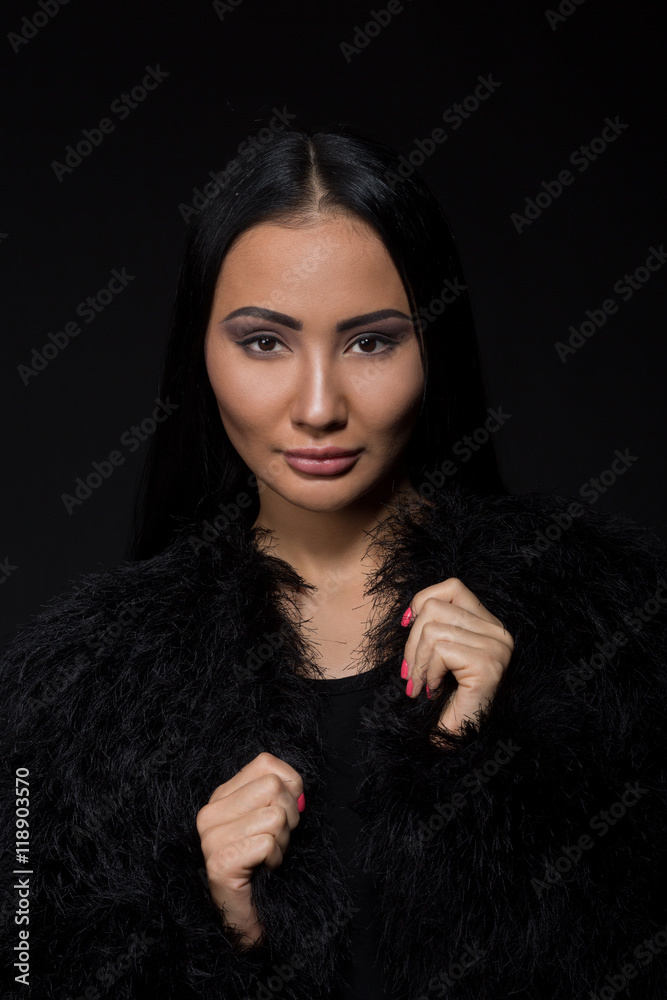 Portrait of brunette model woman posing for photographer in studio. Beautiful lady with black hair wearing expensive fur isolated on black background. Portrait of brunette model woman posing for photographer in studio. Beautiful lady with black hair wearing expensive fur isolated on black background.