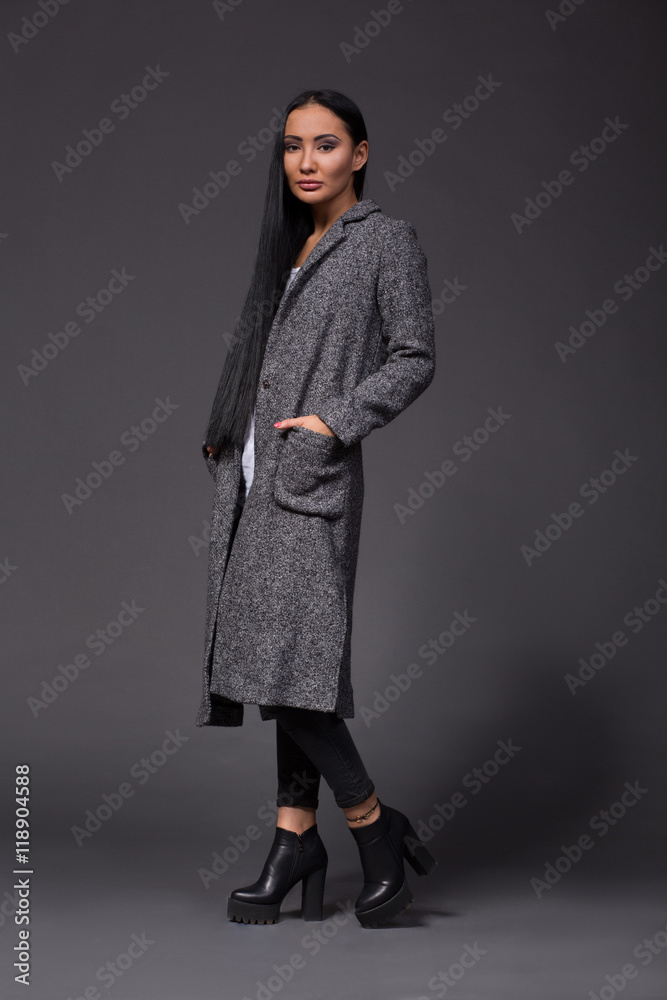Picture of brunette model woman posing in full length while showing beautiful clothed of designers isolated on grey background in studio. Picture of brunette model woman posing in full length while showing beautiful clothed of designers isolated on grey background in studio.