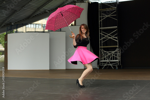 Piękna kobieta tańczy z parasolką na scenie amfiteatru.