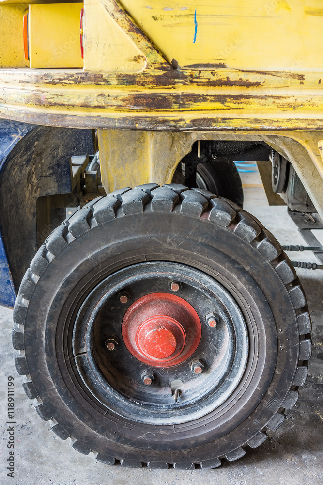 Wheel of old forklift  used in industrial warehouse. The vehicle is also called lift or fork truck.