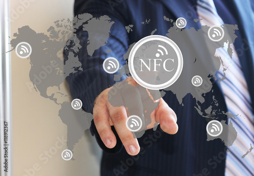 The businessman clicks on the NFC icon on the world map. NFC near field communication network. Web icons.The latest technology. The web icons. photo