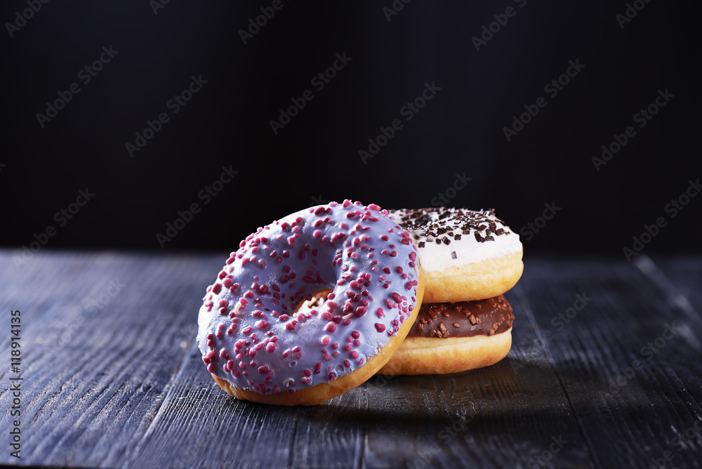 Donuts with blue, chocolate and vanilla icing on a dark background