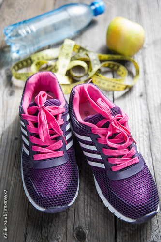 sport shoes, water, apple, centimeter on wooden background