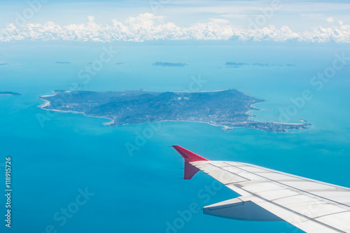 Wing of a plane from window view with Koh Samui in background in Surat Thani, Thailand.
