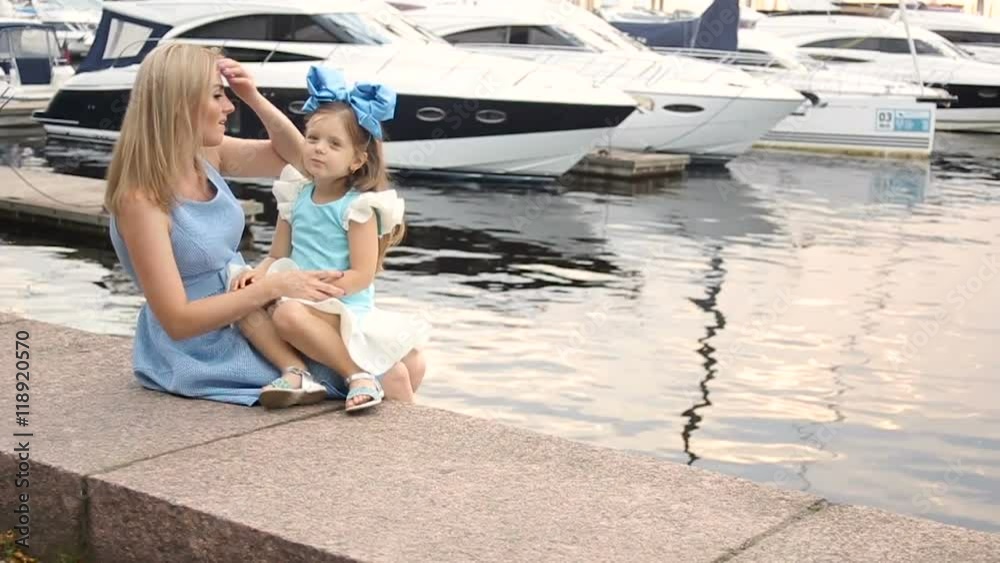 little girl three years sitting on the lap of the mother with long blond hair
