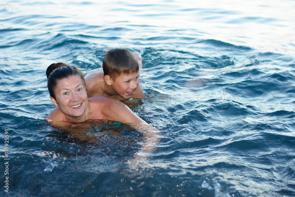 mother with son bathing in the sea