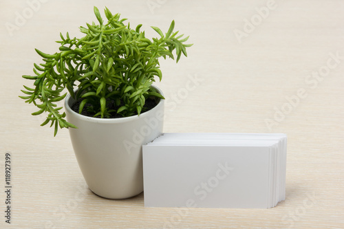White blank business card. Office table desk with set of colorful supplies, cup, pen, pencils, flower, notes, cards on beige background. Top view and copy space for ad text