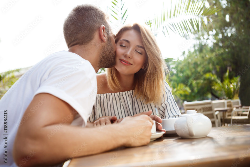 Young beautiful couple speaking, smiling, resting in cafe.
