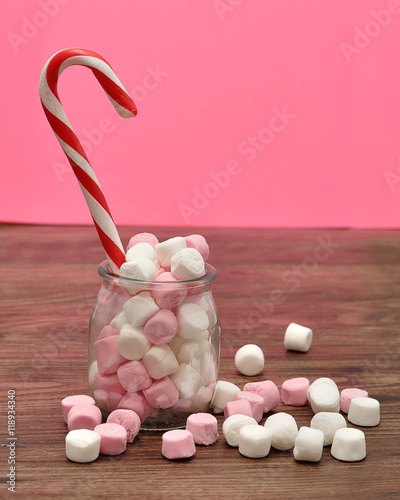 A candy cane in a jar filled with small pink and white marshmall photo