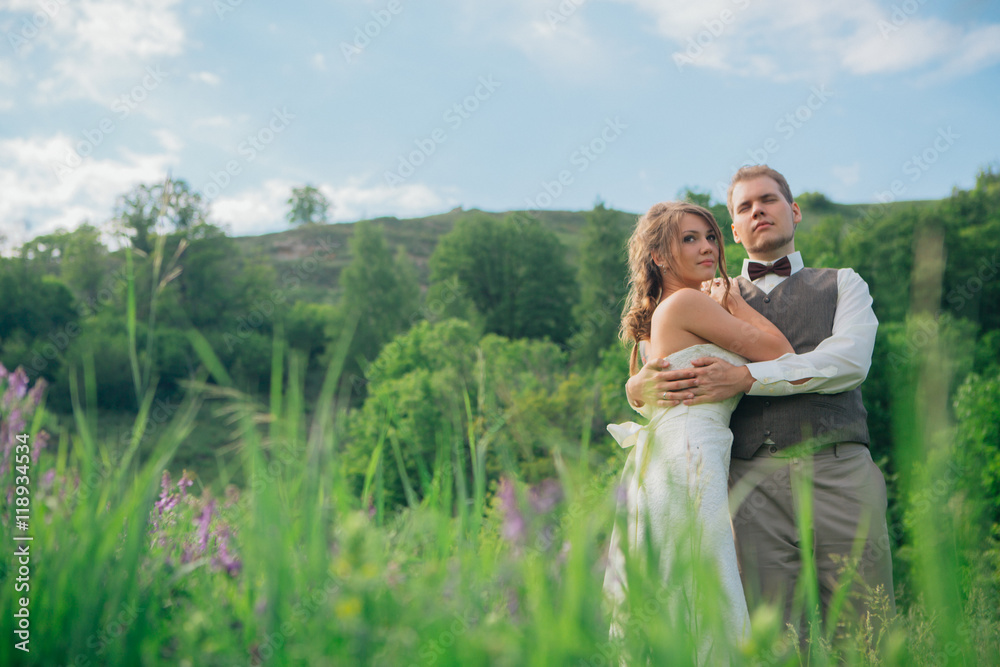 the bride and groom with a bouquet in the grass against the background mountain landscape the bride and groom with a bouquet in the grass against the background mountain landscape