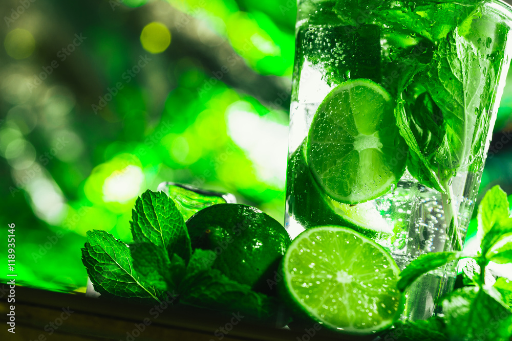 glass of mojito with lime and mint close-up ice cube on a dark background