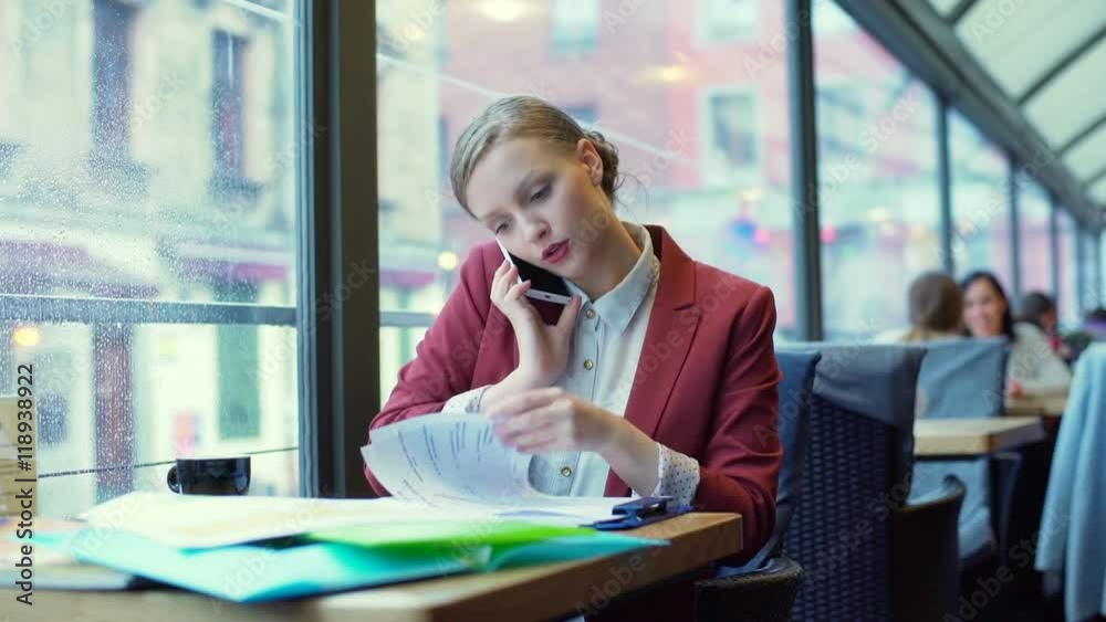 Occupied businesswoman talking on cellphone and checking documents
Occupied businesswoman talking on cellphone and checking documents