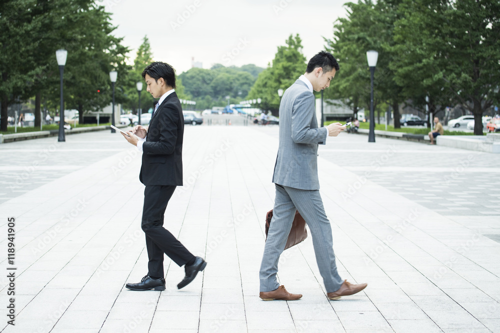 Businessman is using a mobile phone while walking Businessman is using a mobile phone while walking
