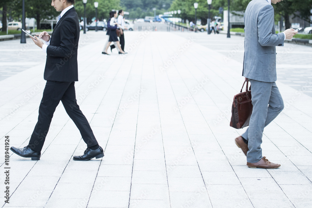 Businessman, looking at a smartphone while walking Businessman, looking at a smartphone while walking
