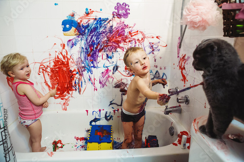 Portrait of two cute adorable white Caucasian little boy and girl playing painting cat with paints in bathroom having fun, lifestyle childhood concept photo