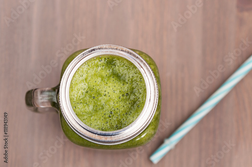 A green smoothie in a mason jar on wooden background