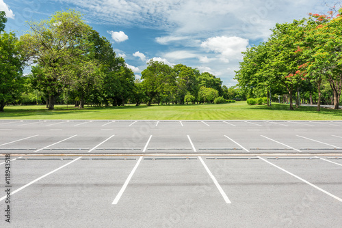 Empty parking lot against green lawn in city park