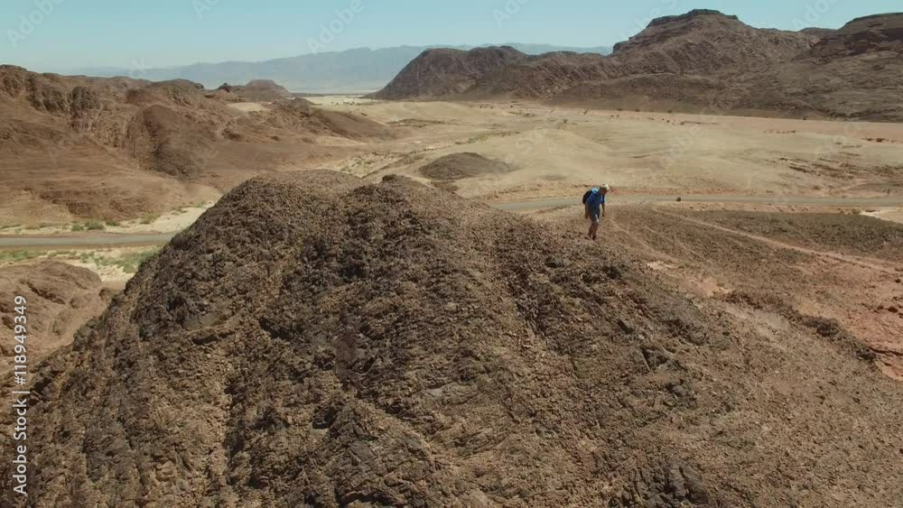 Alone in the desert , a climber reached the summit. Valley of Sodom and Gomorrah. Aerial shot Alone in the desert , a climber reached the summit. Valley of Sodom and Gomorrah. Aerial shot