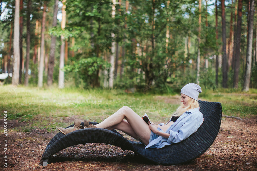 Girl with a book resting on a lounger in a forest glade Girl with a book resting on a lounger in a forest glade