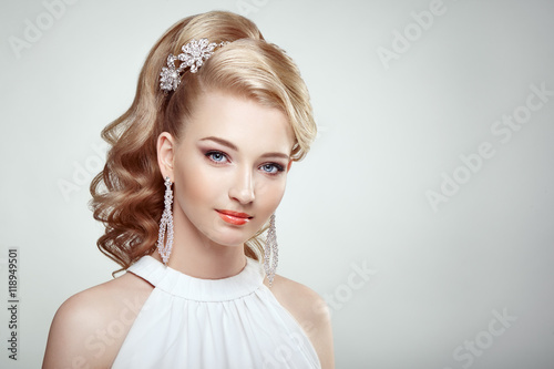 Fashion portrait of young beautiful woman with jewelry and elegant hairstyle. Blonde girl with long wavy hair. Perfect make-up. Beauty style woman with diamond accessories