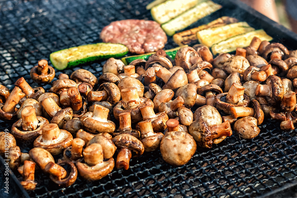 Champignon white mushrooms grilled on grill or BBQ steam and small drops of water. Cooking mushrooms on the grill. Portobello mushrooms marinated and grilling. Grilled vegetables on a grill close up.