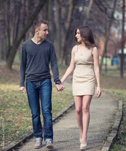 Young, happy and attractive couple enjoying together in walk through the city park. Urban outdoors.