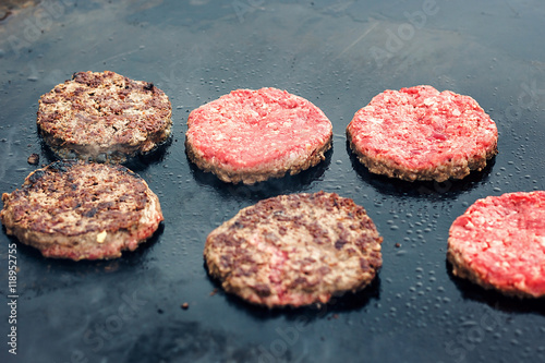 Fresh healthy hamburgers cooking on pan under flaming coals. Meat roasted on fire barbecue kebabs on the grill. Grilled burger cutlet beef minced meat patties or frikadeller in a pan
