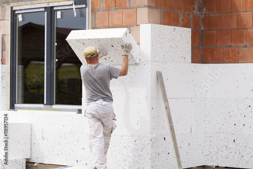 Billede på lærred Workers spreading mortar over styrofoam insulation and mesh with trowel