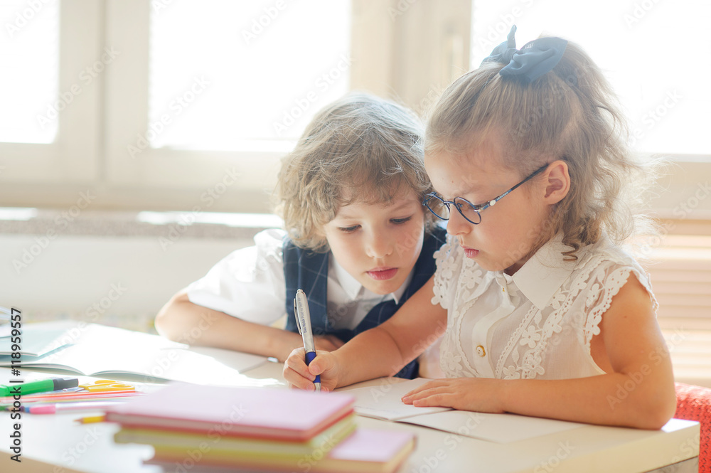 Φωτογραφία Little schoolboy and schoolgirl diligently doing their homework.
