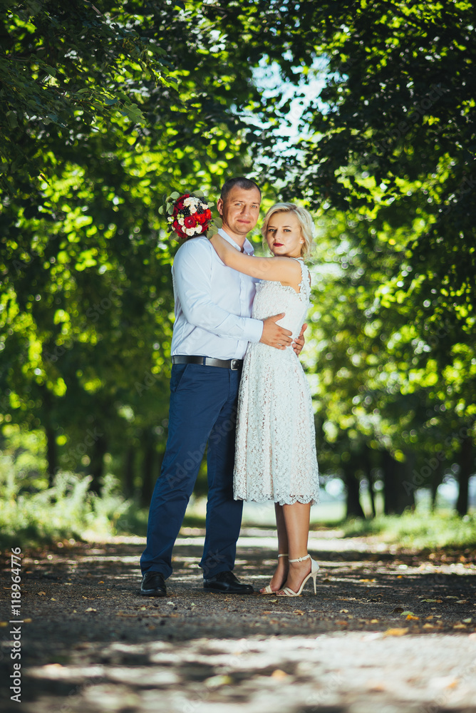 Fototapeta premium Bride and groom at wedding day, walking outdoor at summer on nature. Bridal couple, happy newlywed woman and man embracing. Loving wedding couple outdoor.