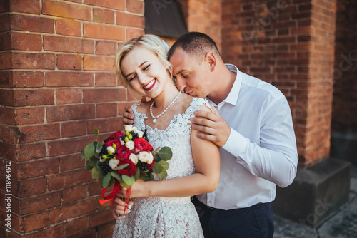 Bride and groom at wedding Day walking Outdoors near architecture. Bridal couple, Newlywed woman and man embracing with love