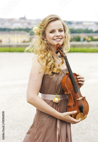 Beautiful smiling girl with a violin outdoor.Beautiful smiling girl playing on the violin outdoors. Musician for the wedding.Violin under the open sky 