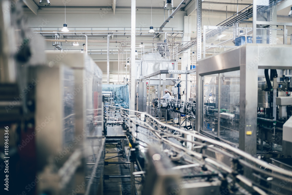 Naklejka premium Industrial interiors. Robotic factory line for processing and quality control of pure spring water bottled into canisters. Low light and small amount of noise visible. 