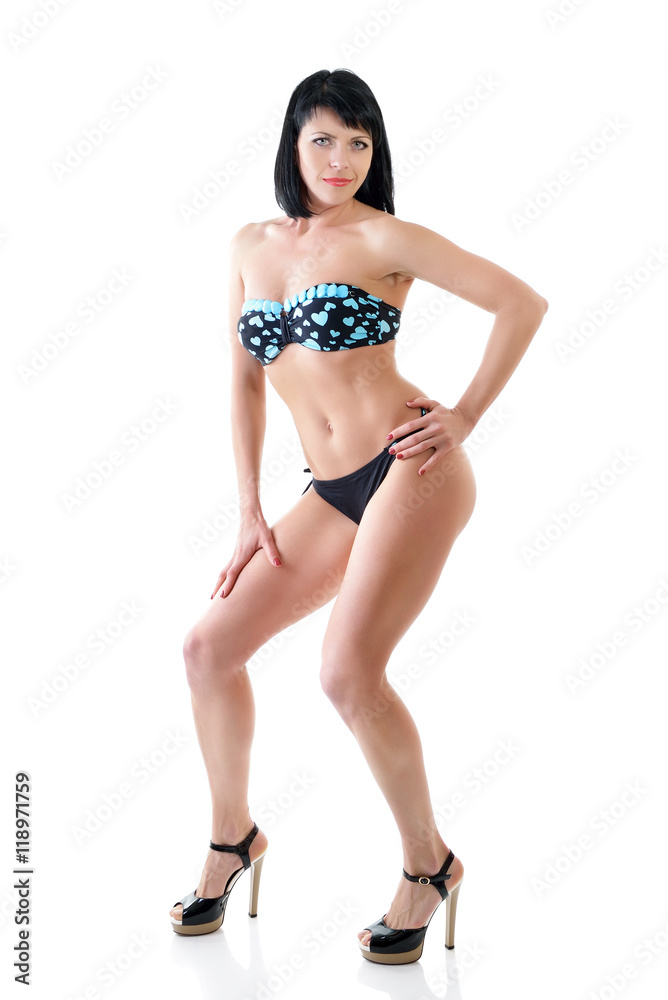 Mid adult young fit woman posing in studio in swimsuit over whit