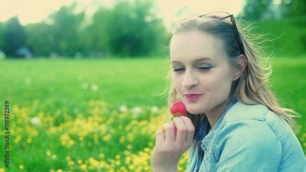 Pretty girl eating strawberry and smiling to the camera on the meadow
Pretty girl eating strawberry and smiling to the camera on the meadow