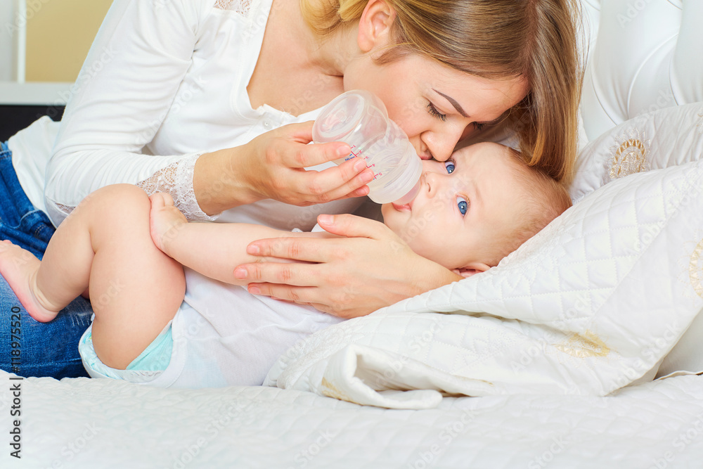 The concept of caring for the baby. Mother feeding baby with mil The concept of caring for the baby. Mother feeding baby with mil