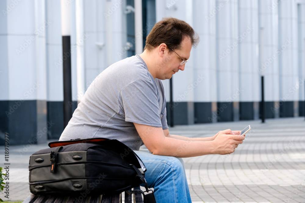 Middle age man reading tablet sitting outdoors