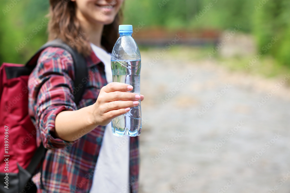 Woman holding bottle with fresh water on blurred background Woman holding bottle with fresh water on blurred background