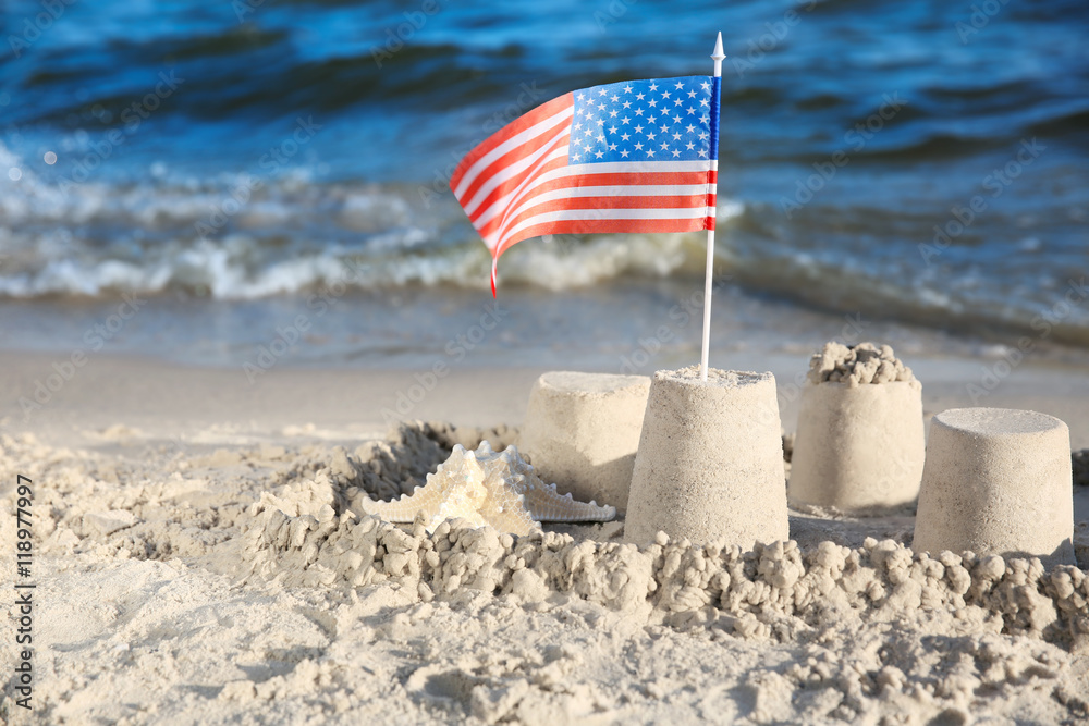 Naklejka premium Sand castle with American flag on beach