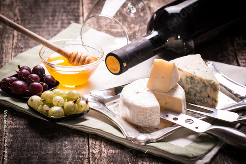 Composition of cheese, berries, bottles and glasses of wine on a wooden table