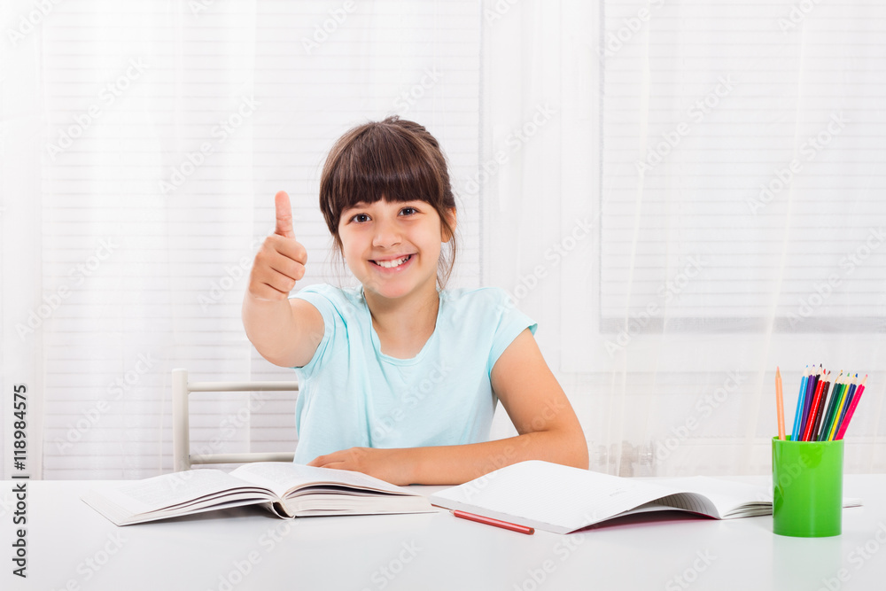 Cute little girl is showing thumbs up while she is doing her homework. Cute little girl is showing thumbs up while she is doing her homework.