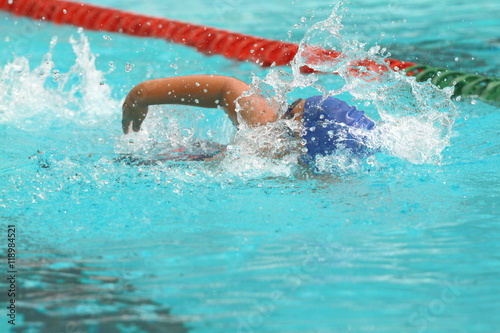Young Asian man wearing blue cap swims freestyle stroke in a swimming pool for competition © wibulpas