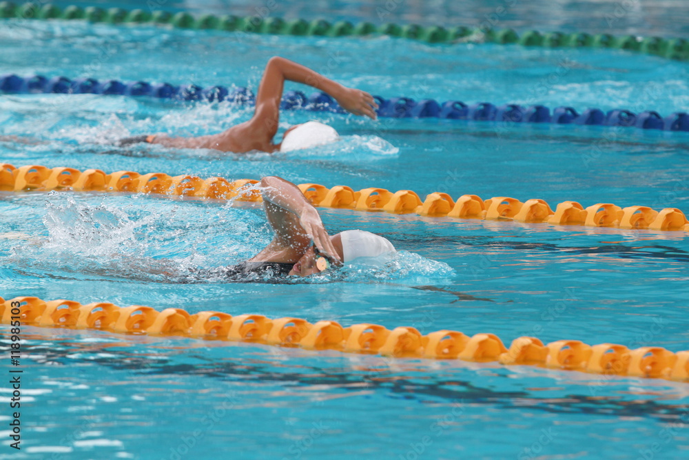 two swimmers beating each other on freestyle stroke in a swimming pool for competition or race