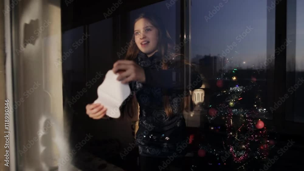 Two little girls decorate a window with the help of artificial snow. Preparing for the New Year and Christmas.