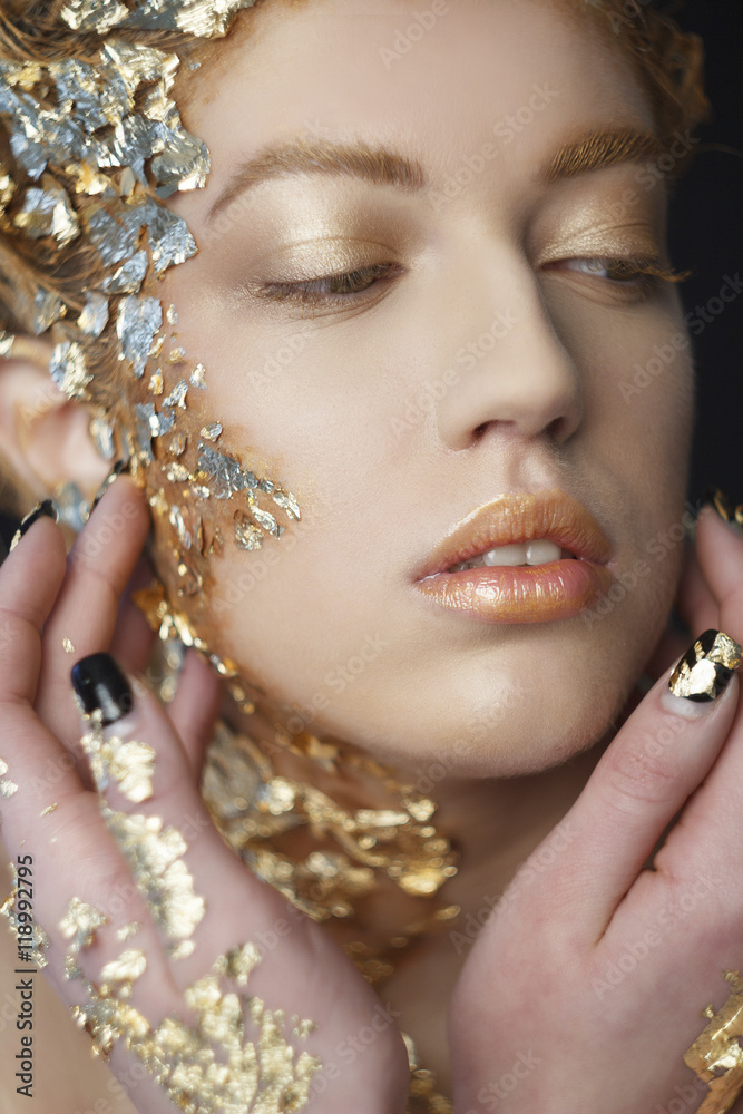 Portrait of beautiful sexy model with gold foil on her face